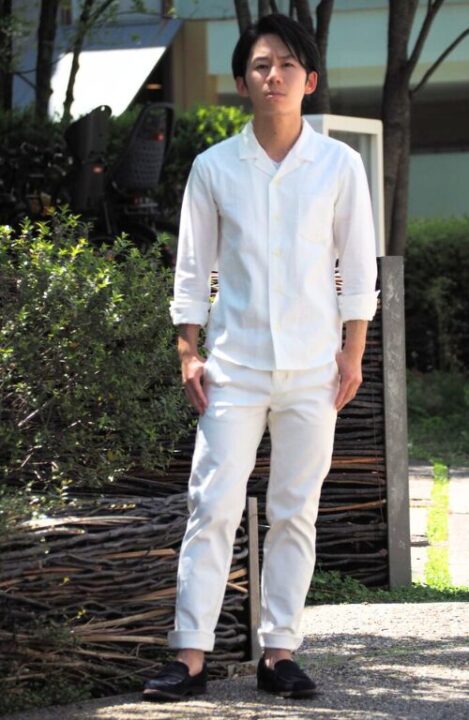 白いシャツと白いパンツを着用し、シャツの袖とパンツのすそをロールアップした男性