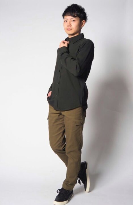 黒色のシャツとカーキ色のカーゴパンツ、スニーカーを着用した男性